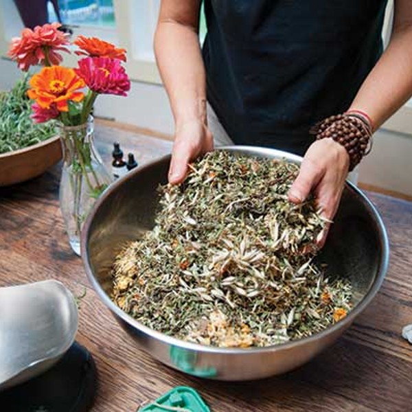 Dana Eudy mixing calendula, comfrey, oats, and plantain that will be infused in oil to make a healing salve.