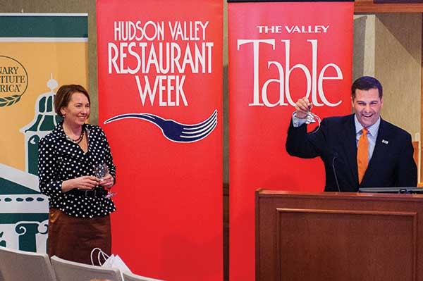 Dutchess County Executive Marc Molinaro rings a bell declaring the opening of the seventh annual Hudson Valley Restaurant Week while Valley Table publisher Janet Crawshaw looks on at the Culinary Institute of America in Hyde Park on February