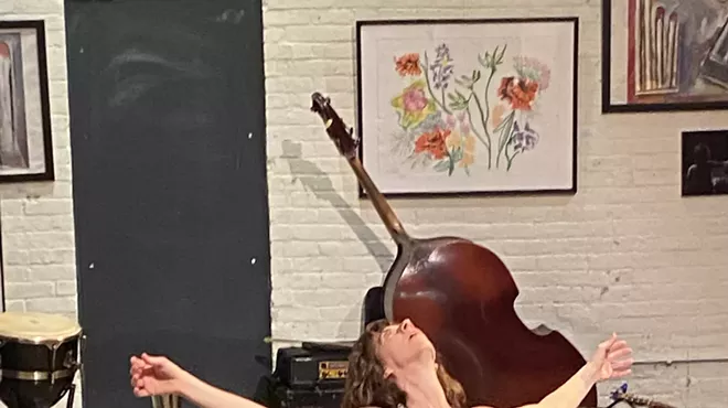 A dancer with one knee on the floor and their arms open.