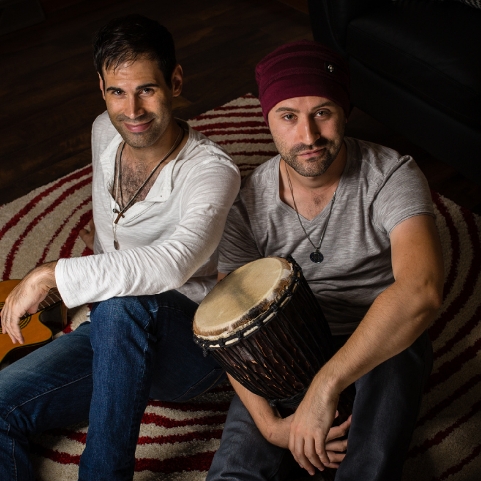 Two members of the World Rock Fusion band Novus Cantus sitting together on a colorful carpet